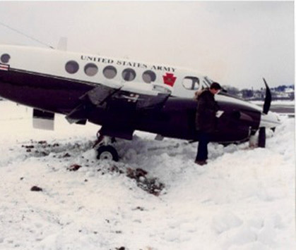 United States Army plan crashed in snow with two men around it documenting